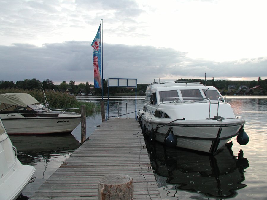 Hausboot und Sportboot an einem Holzsteg in Mirow.