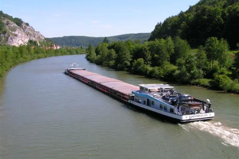 Frachtschiff auf einem Fluss zwischen bewaldeten Ufern