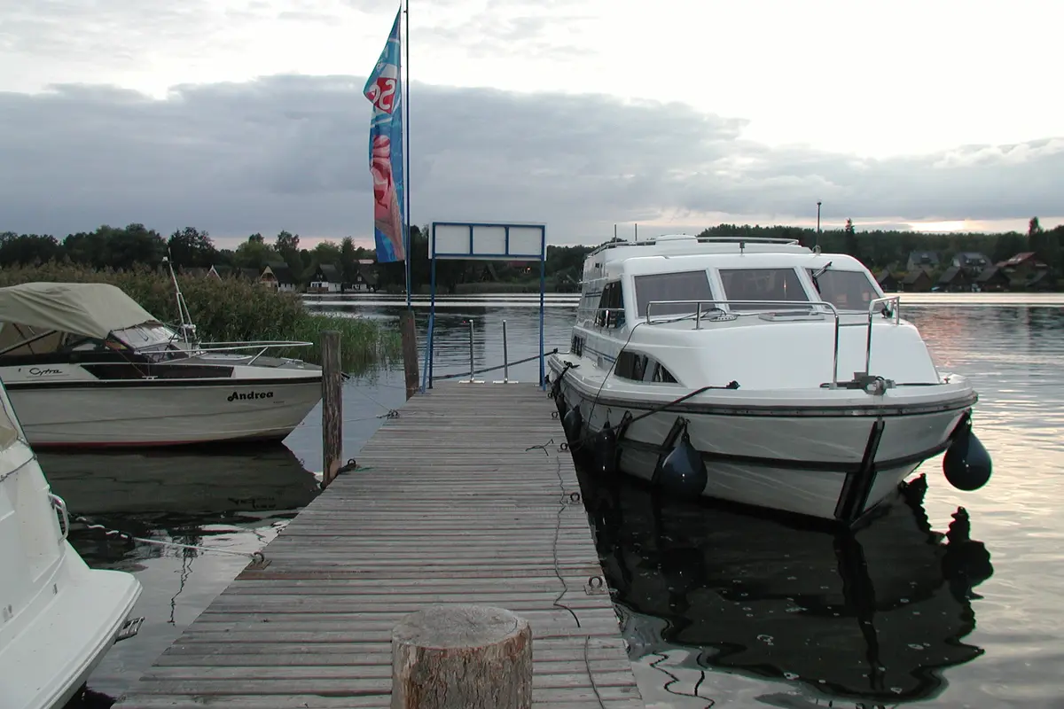 Hausboot an einem Holzsteg auf einem ruhigen See